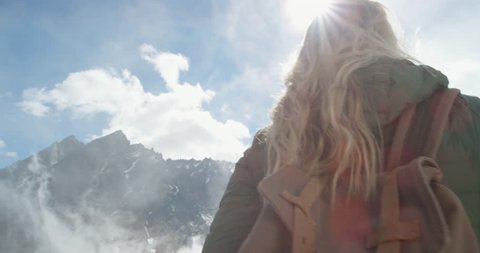 Close up portrait of Woman at top of mountain in nature with blonde hair blowing in wind above the clouds view Hiker Girl in Norway Slow Motion
