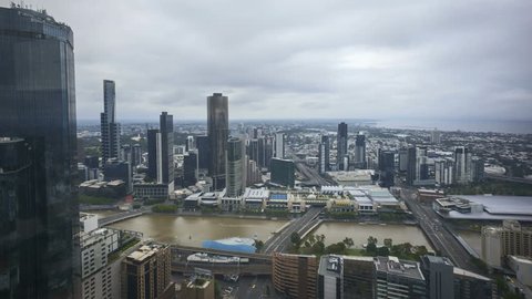 An aerial view of Melbourne cityscape including Yarra River and Victoria Harbour in the distance. Cloudscape time lapse during day light time with moving clouds. 