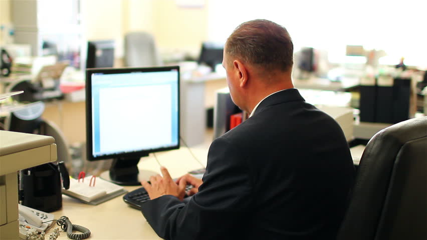 businessman sitting at the computer in the office. View from the back.