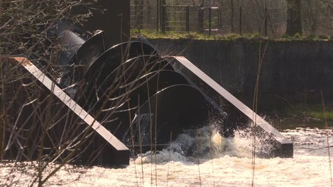 archimedean screw hydro turbine rotating, splashing water - medium shot. The fish friendly hydroelectric power plant produces green energy. RIVER DOMMEL, THE NETHERLANDS