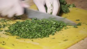 CLoseup of chef's hands chopping dill with knife