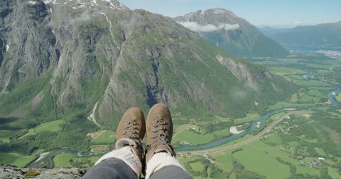 Close up hiking boots of Independent Woman traveller on top of mountain looking at view Hiker girl dangling feet over edge of cliff enjoying vacation travel adventure nature Romsdalen Valley Norway