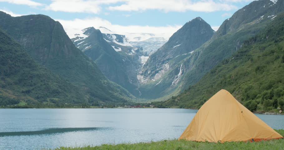 Woman standing next to tent at edge of lake looking at view Camping girl in scenic landscape enjoying vacation travel adventure nature Norway