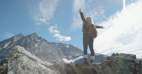 Independent Woman traveller with arms raised on top of mountain looking at view Hiker girl lifting arm up celebrating scenic landscape enjoying vacation travel adventure nature Romsdalen Valley Norway