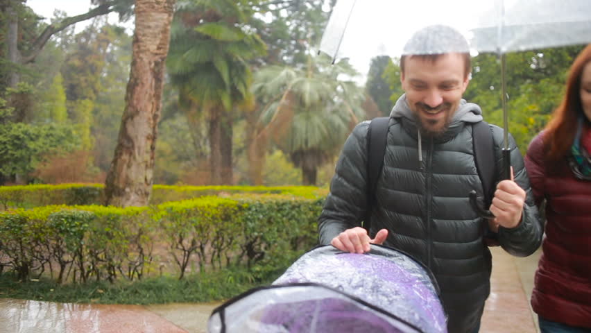 Mom and Dad, playing with their child, sitting in a stroller: walk in the park