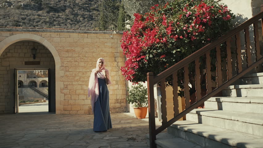 Beautiful woman in long dress and headscarf going upstairs