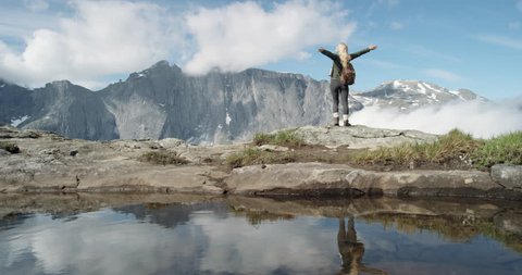 Woman with arms raised on top of mountain looking at view Climber girl lifting arm up celebrating scenic landscape enjoying vacation travel adventure nature Romsdal Valley Norway