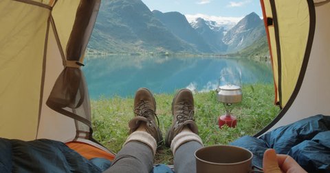 Camping woman lying in tent Close up of Girl feet wearing hiking boots relaxing on vacation POV