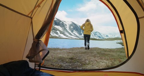 Camping woman climbing out of tent taking photo beautiful lake relaxing on vacation POV Norway