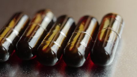Medicine And Drugs. Oil pills turning on silver background. Macro shot.
