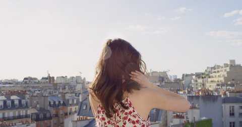 Rear view Woman looking at Paris cityscape background view from rooftop enjoying European vacation travel adventure