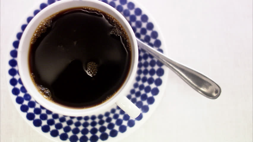 Adding a lump of sugar to a cup of coffee.