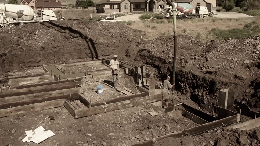 Construction workers prepare and pour the footings of a house.
