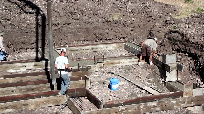 Construction workers prepare and pour the footings of a house.