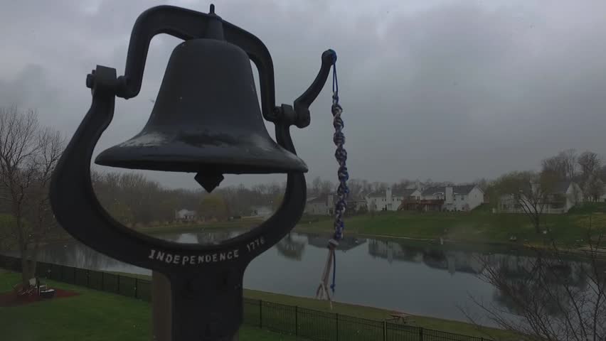Snowfall in early March in the American suburbs with freedom bell and lake view, overcast sky. smooth handheld movement