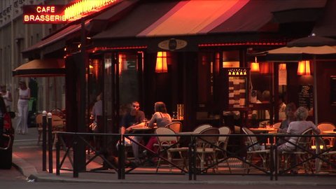 Paris, France - CIRCA June, 2006: People sit at an outdoor table talking and smoking at a cafe during dusk