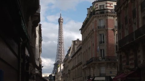 Paris, France - CIRCA June, 2006: View of the Eiffel Tower with a picturesque cloudy sky behind it as seen from the street between some classic buildings