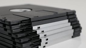 Close-up of floppy disc classic magnetic storage media on white 4K 2160p 30fps UHD tilting footage - Old black diskette data archives stacked 3840X2160 UltraHD video