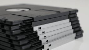 Tilting on floppy disc classic magnetic storage media on white 4K 2160p 30fps UHD footage - Old black diskette data archives stacked 3840X2160 UltraHD video