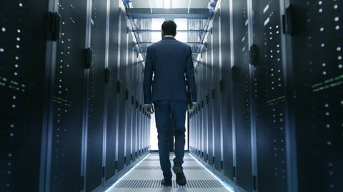 Following Shot of IT Engineer Walking Through Data Center with Rows of Working Rack Servers on Both Sides. Shot on RED EPIC-W 8K Helium Cinema Camera.