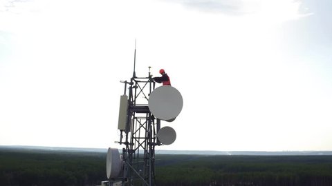 great heights maintenance worker, drone view of telecommunication repeater antenna system, radio master works at great heights of tv or radio tower