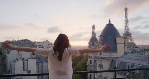 Young tourist woman stretching in morning on hotel balcony with view of Eiffel Tower Paris arms raised enjoying european travel adventure celebrating beautiful city sightseeing exploration