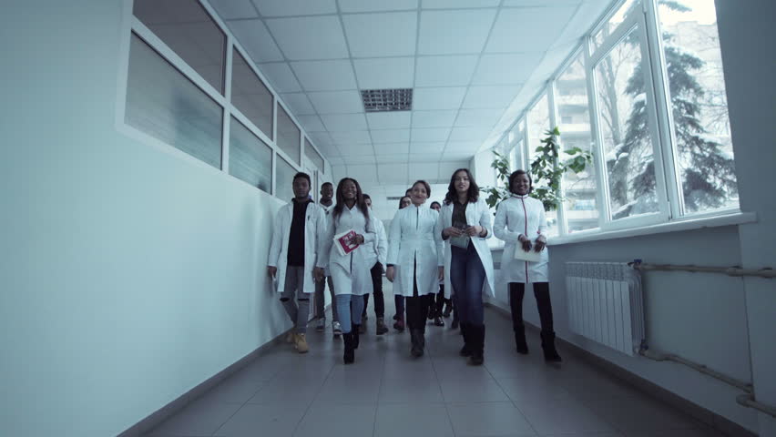 A group of medics walking in the corridor and looking at camera