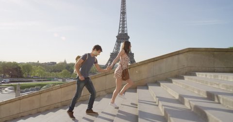 Young couple holding hands woman leading boyfriend walking towards view of Eiffel Tower Paris travel concept