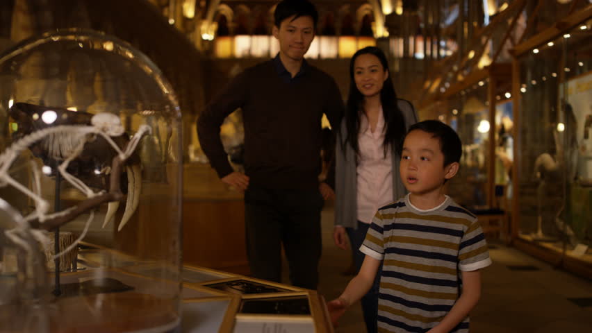 4K Asian family in natural history museum looking at a skeleton inside glass jar
