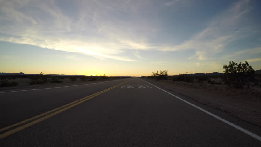 Route 66 pavement sign driving shot after sunset in the California Mojave Desert.
