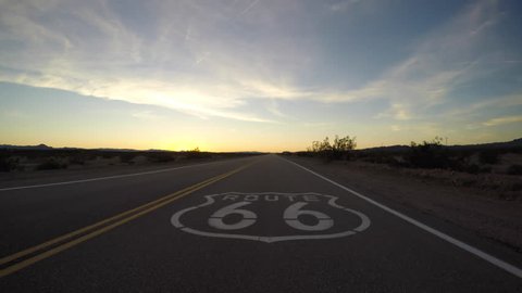 Route 66 pavement sign driving shot after sunset in the California Mojave Desert.