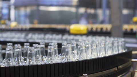 Spill in glass bottles at the plant. Conveyor belt with glass bottles. The production process of alcoholic beverages. close-up