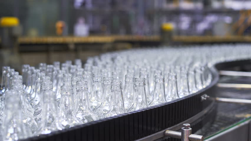 beer production line in the workshop. Bottles Moving Along the Conveyor Line. Glass manufacturing machine. Close-up