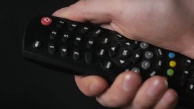 Close-up remote controller TV in hand on black background isolated