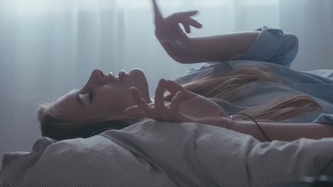 HANDHELD CU Young Caucasian teen girl lying on bed and enjoying music from a vinyl turntable via headphones. 4K UHD RAW edited footage