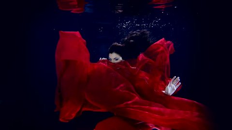 Underwater fairy tale with a young girl athlete in long red dress.