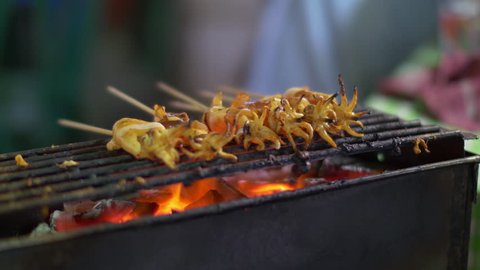 Traditional street food of Thailand. Cooking small squids on the grill at night streetfood fair Stock Video