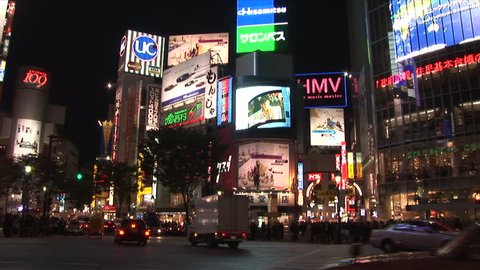 Tokyo, Japan - CIRCA November, 2006: Traffic drives past the camera in a busy intersection with many large billboards during the evening rush hour