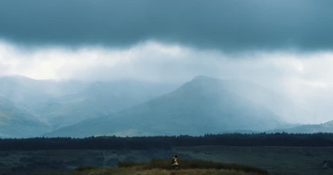 Woman hiking in extreme weather Independent traveler girl is brave in face of uncertainty and climate change storm mountain view landscape nature background enjoying vacation travel adventure Scotland
