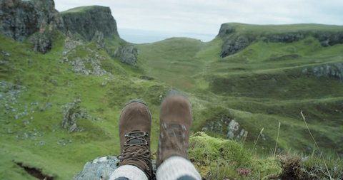 Close up hiking boots of Independent Woman traveller on top of mountain looking at view Hiker girl dangling feet over edge of cliff enjoying vacation travel adventure nature Scotland