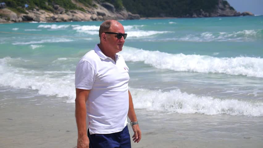 Middle-Aged Successful Man Walking on Beach on Holidays