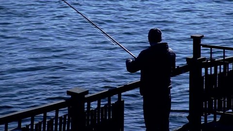 Fisherman fishing with spinning, silhouette