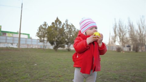 Little girl greedily bites apple and runs away