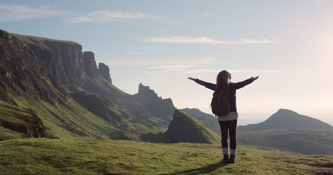 Woman with arms raised on top of mountain looking at view Hiker Girl lifting arm up celebrating scenic landscape enjoying nature vacation travel adventure Quiraing Walk on the Isle of Skye in Scotland