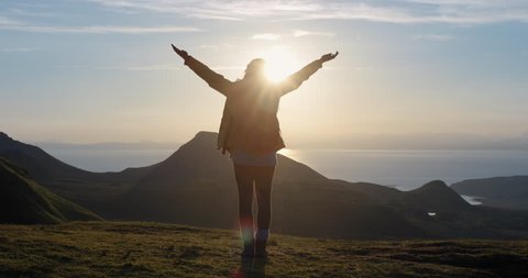 Woman with arms raised on top of mountain looking at Sunrise view Hiker Girl lifting arm up celebrating scenic nature landscape enjoying vacation travel adventure Isle of Skye Scotland