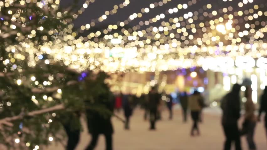 People walking on Christmas market. Christmas shopping/People silhouettes walking on the Christmas market. Strong back light from small cabins on the market. 