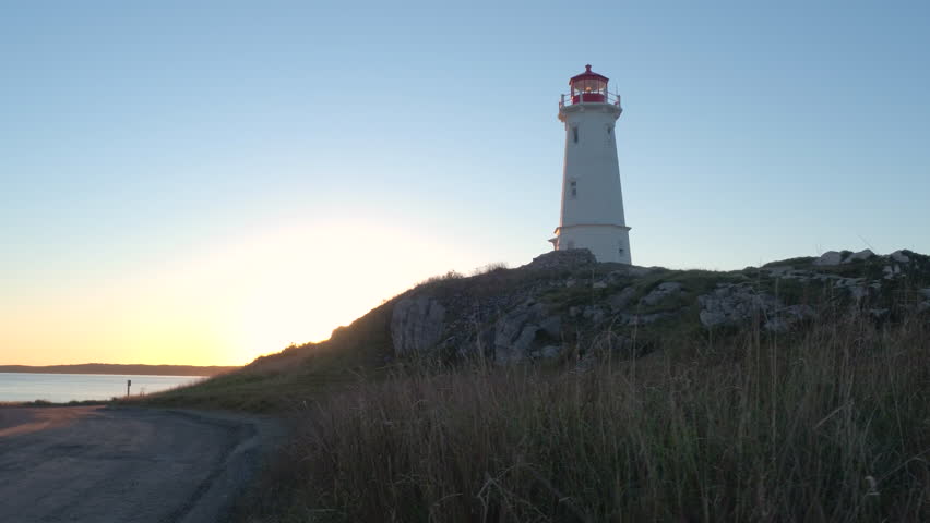 Beautiful octagonal concrete Louisbourg Lighthouse decorated with neoclassical architectural features standing on the rocky seashore rising above North Atlantic Ocean on Nova Scotia peninsula, Canada
