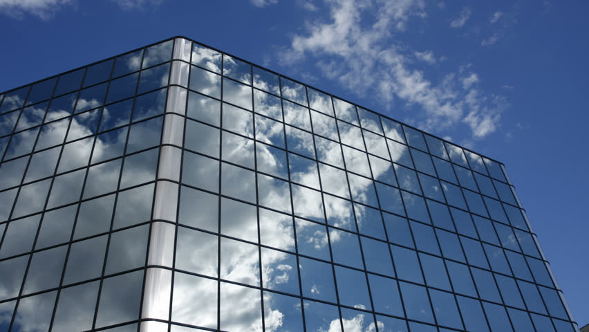 Active clouds are reflected in the mirrored windows of an office building. HD