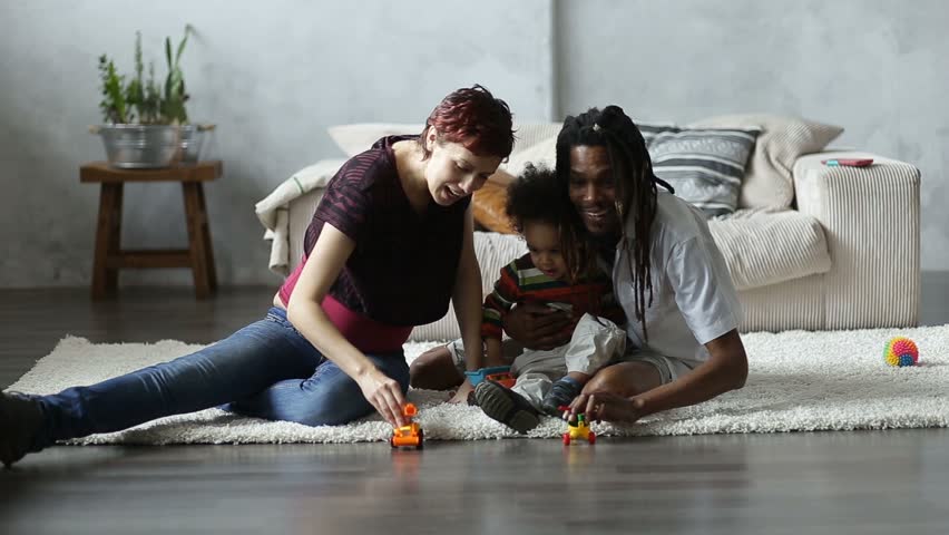 Happy parents playing with toddler son on floor
