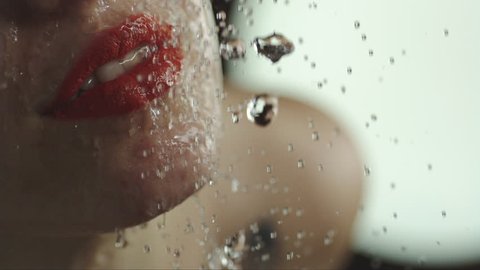 woman taking a shower in slow motion. beautiful girl with lipstick under a shower enjoying. mouth  and lips close up